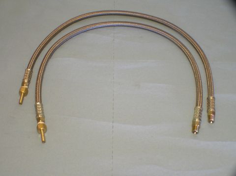 2000 Ford Excursion - Two braided metal hoses with brass fittings are laid out on a light gray surface.