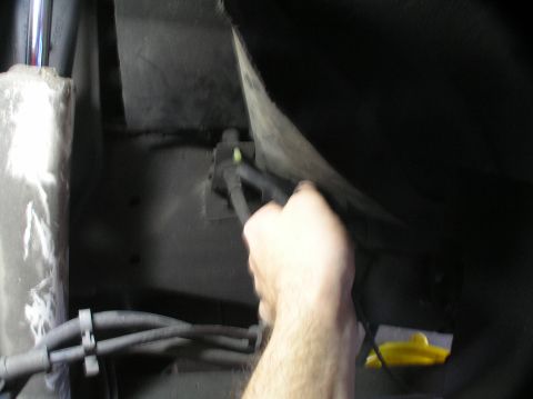 2000 Ford Excursion - A hand works on braided lines, likely for a vehicle's 4x4 system, in a dark undercarriage area.