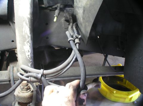 2000 Ford Excursion - A mechanic is shown working on the brake lines of a vehicle, with a drain pan underneath.