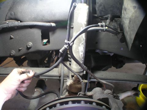 2000 Ford Excursion - A close-up view of brake lines and suspension components on a vehicle's undercarriage.