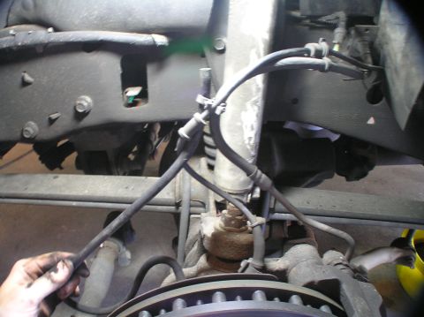 2000 Ford Excursion - Close-up view of braided lines associated with the ESOF/4x4 system, near the brake rotor and suspension components.