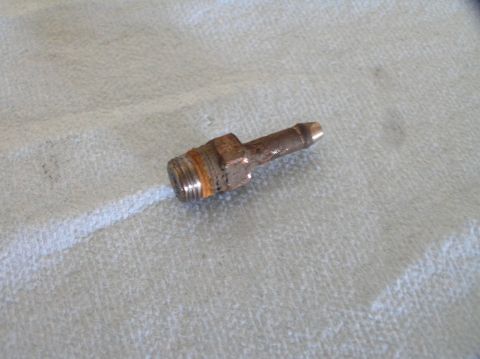 2000 Ford Excursion - A close-up view of a metal fitting with a threaded end and a barbed tip, resting on a textured cloth surface.