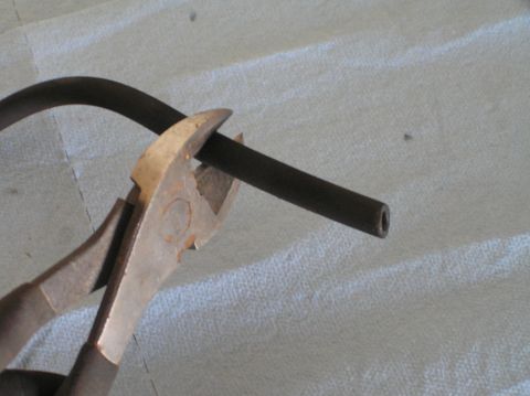2000 Ford Excursion - Wire cutters are used to cut a dark, flexible hose.