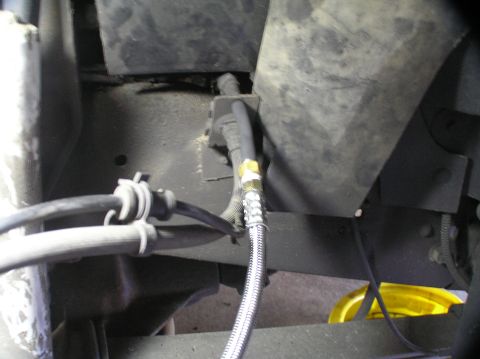 2000 Ford Excursion - Close-up view of braided hoses and mechanical components on a vehicle's undercarriage.