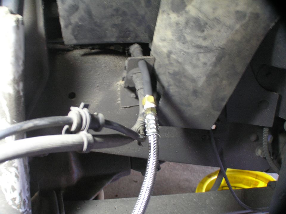 Braided stainless brake/flex line with fitting under a vehicle chassis