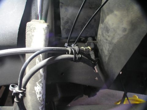 2000 Ford Excursion - Close-up view of braided lines and a shock absorber, likely part of a vehicle's suspension system.