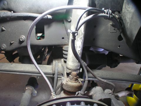 2000 Ford Excursion - Close-up view of braided brake lines and suspension parts on a vehicle.