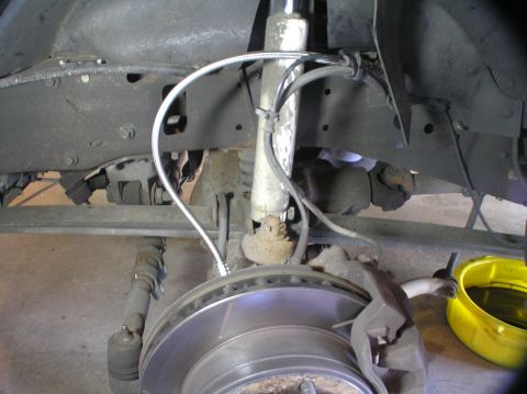 2000 Ford Excursion - The front suspension and brake components of a vehicle are visible, including a shock absorber and brake lines.