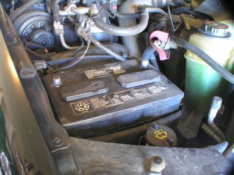2000 Ford Excursion - Close-up view of an Optima Yellow-top D34 battery located in the engine bay, alongside a green fluid reservoir.