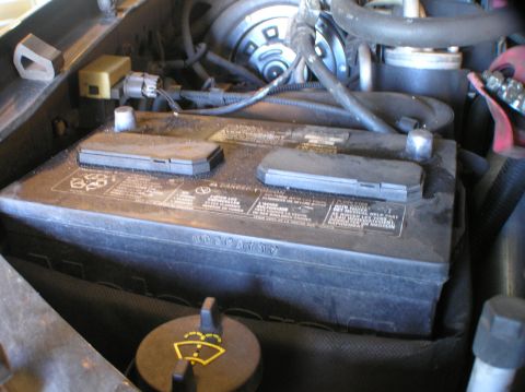 2000 Ford Excursion - Close-up of a car battery located in the engine bay, showing various warning labels.