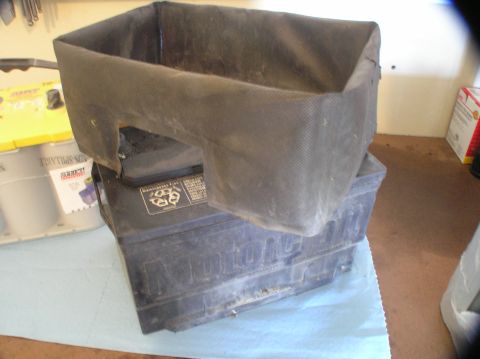 2000 Ford Excursion - Two car batteries are stacked, one covered by a dark fabric, with visible text on the battery labels.
