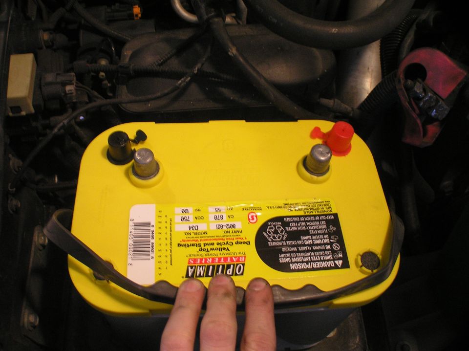Yellow Optima YellowTop battery installed in engine bay, red cap on positive terminal
