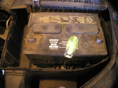 2000 Ford Excursion - A Motorcraft car battery is shown with a screwdriver used to secure its hold-down bracket.