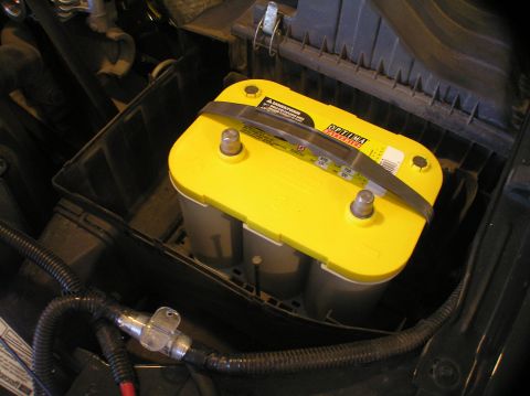 2000 Ford Excursion - Close-up of a yellow Optima battery, showing its terminals and branding.