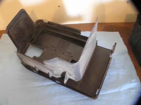 2000 Ford Excursion - A brown plastic battery tray is shown from an elevated angle, resting on a white cloth.