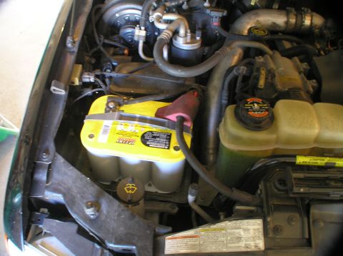 2000 Ford Excursion - Close-up view of an engine bay, focusing on a yellow Optima battery and associated engine components.