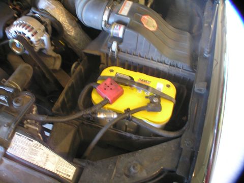 2000 Ford Excursion - Close-up view of an engine bay, focusing on a yellow Optima battery and associated engine components.