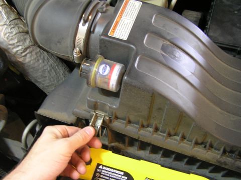 2000 Ford Excursion - Close-up of a vehicle's air intake system, showing a hand interacting with a latch on the housing.