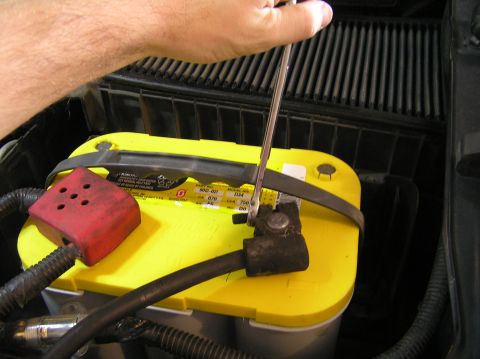2000 Ford Excursion - A hand uses a wrench to tighten a car battery terminal.