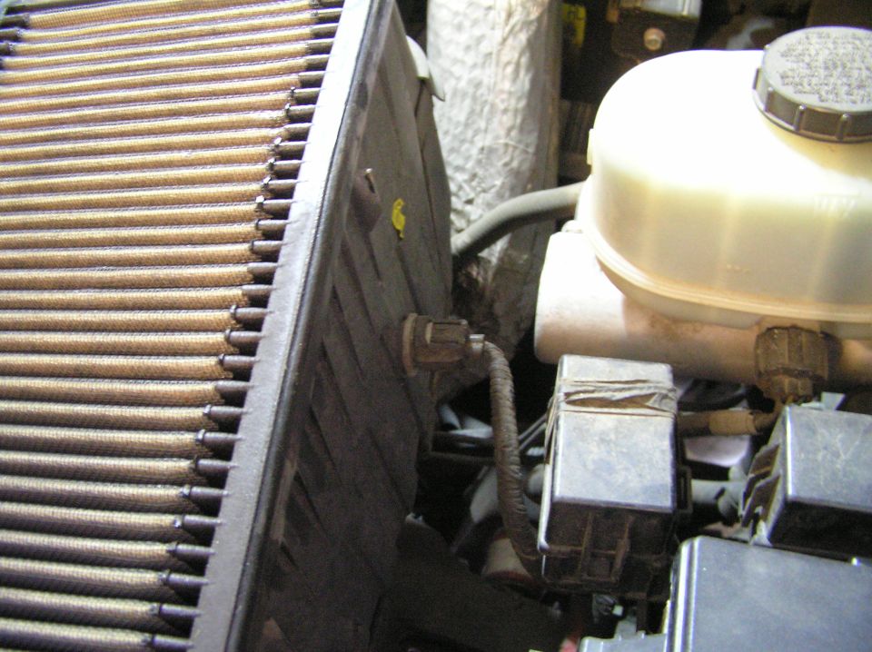 Engine bay with radiator core, brake fluid reservoir, and rusty components