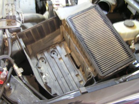 2000 Ford Excursion - Engine bay view of a removed air filter housing and its filter element.