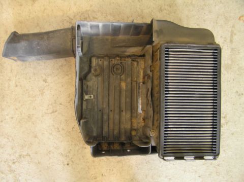 2000 Ford Excursion - A dirty black plastic air intake box with a gray filter element is shown from above.