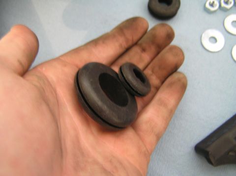 2000 Ford Excursion - Two rubber grommets of different sizes are held in a dirty hand, with hardware visible in the background.