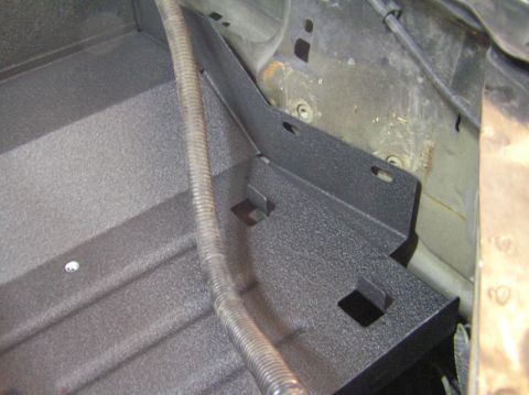 2000 Ford Excursion - Close-up view of a textured black bracket in the engine bay, with a ribbed hose running alongside it.