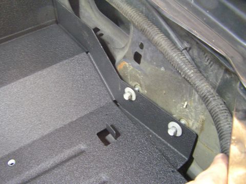 2000 Ford Excursion - Close-up of a black textured plastic tray and its mounting bracket, attached to the vehicle's chassis.