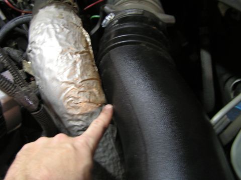 2000 Ford Excursion - Close-up view of engine components, including an intake tube and heat shield.