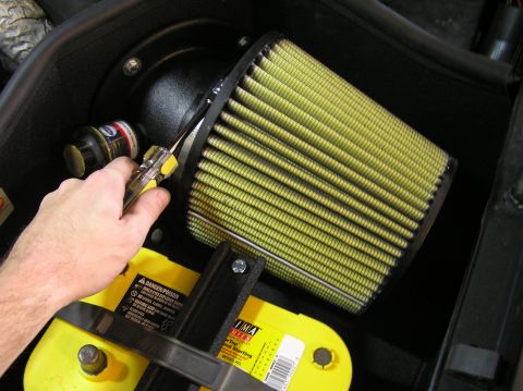 2000 Ford Excursion - Close-up of an engine air filter and battery installation, with a hand holding a tool.