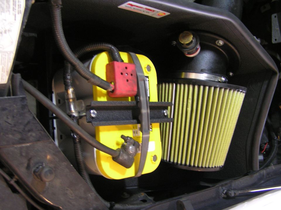 Engine bay with yellow component, black bracket, and conical yellow air filter on intake tube