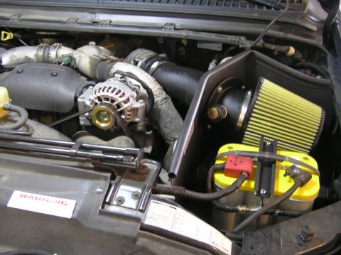 2000 Ford Excursion - Aftermarket air intake and yellow battery installed in an engine bay.