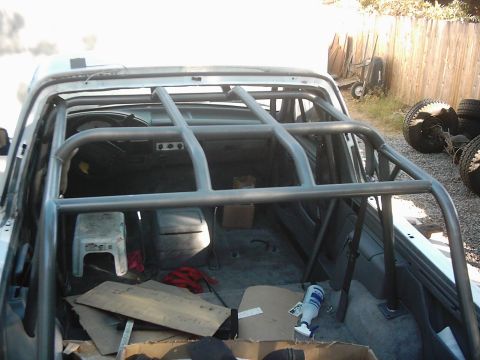 1978 Ford Bronco - The interior of a vehicle is shown with a newly installed roll cage and various items scattered around.