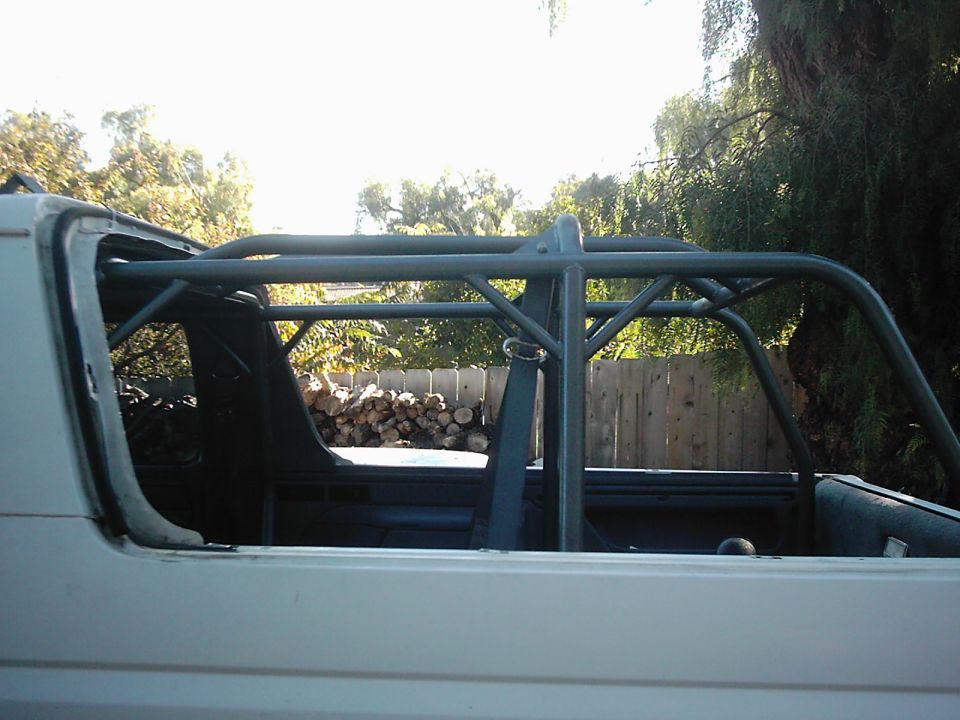 White 1978 Ford Bronco side view with interior roll cage and cut-off top