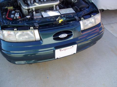 1995 Ford Taurus - Front view of a dark green 1995 Ford Taurus with its hood open, revealing the engine compartment.
