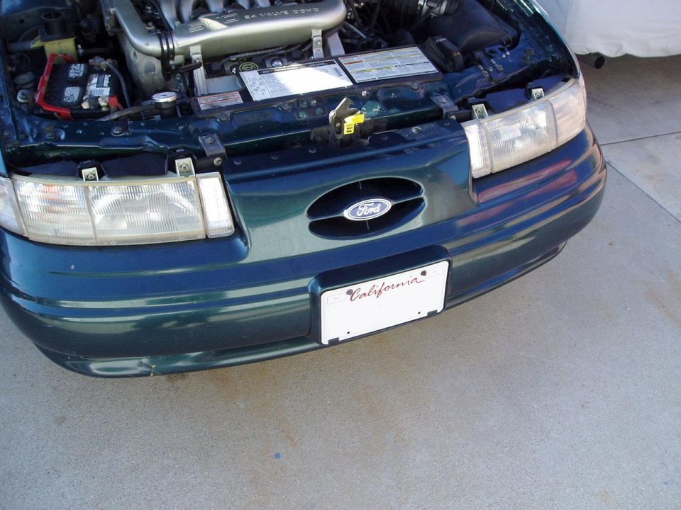 Green 1995 Ford Taurus front end with hood open, showing engine and California license plate