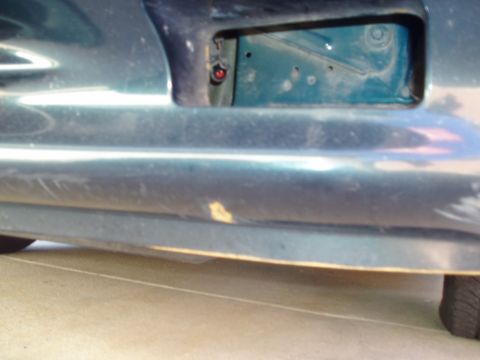 1995 Ford Taurus - Close-up of a car's bumper section with a cutout, showing internal components and a red electrical connector.