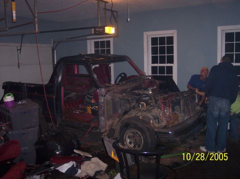 1994 Ford Bronco - 1994 Ford Bronco undergoing teardown in a garage with the front end disassembled.