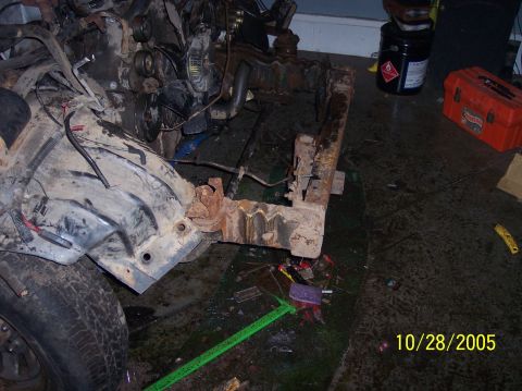 1994 Ford Bronco - Vehicle frame and engine components are disassembled on a garage floor, with a measuring tape visible.