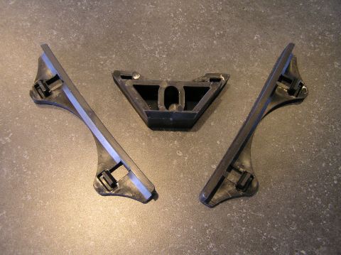 2000 Ford Excursion - Three black plastic battery hold-down brackets are arranged on a textured gray surface.