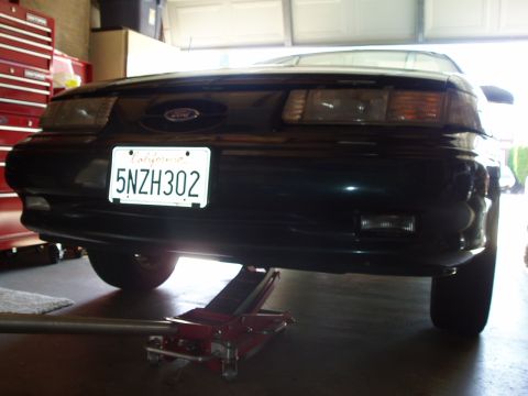 1995 Ford Taurus - Front view of a 1995 Ford Taurus, supported by a floor jack in a garage.