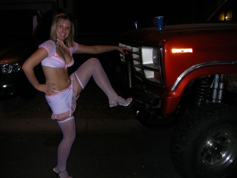1984 Ford Bronco - A woman poses next to a red lifted truck, possibly a Ford Bronco, with its front end prominently displayed.