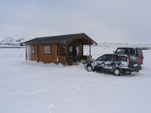 2001 Jeep Wrangler - Two vehicles are parked in a snowy landscape next to a small log cabin, with mountains in the background.