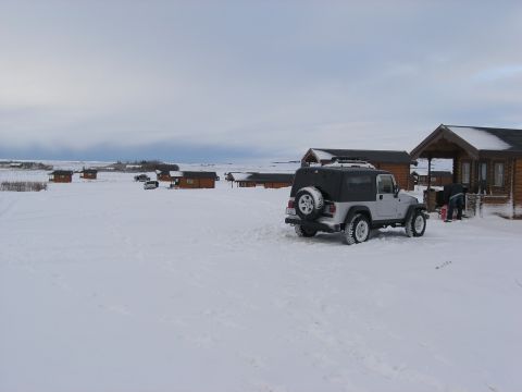 2001 Jeep Wrangler - A silver 2001 Jeep TJ is parked in the snow near several cabins, with another vehicle visible in the background.