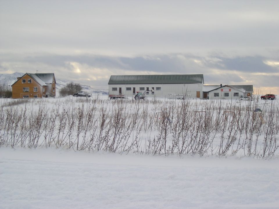 Snowy farm scene with buildings and vehicles