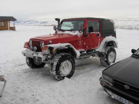 2001 Jeep Wrangler - A red 2001 Jeep TJ is parked in the snow, with a black car partially visible on the right.