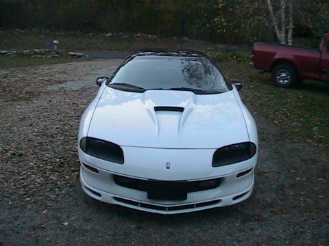 1996 Chevrolet Camaro - Front view of a white 1996 Chevrolet Camaro with a custom hood scoop, parked outdoors. A red pickup is in the background.
