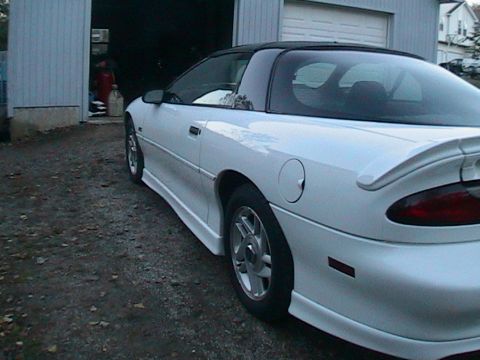 1996 Chevrolet Camaro - A white 1996 Chevrolet Camaro with a black t-top roof is parked outside a garage.