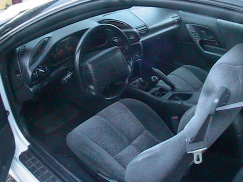 1996 Chevrolet Camaro - The interior of a 1996 Chevrolet Camaro features a dark dashboard, steering wheel, and cloth seats.